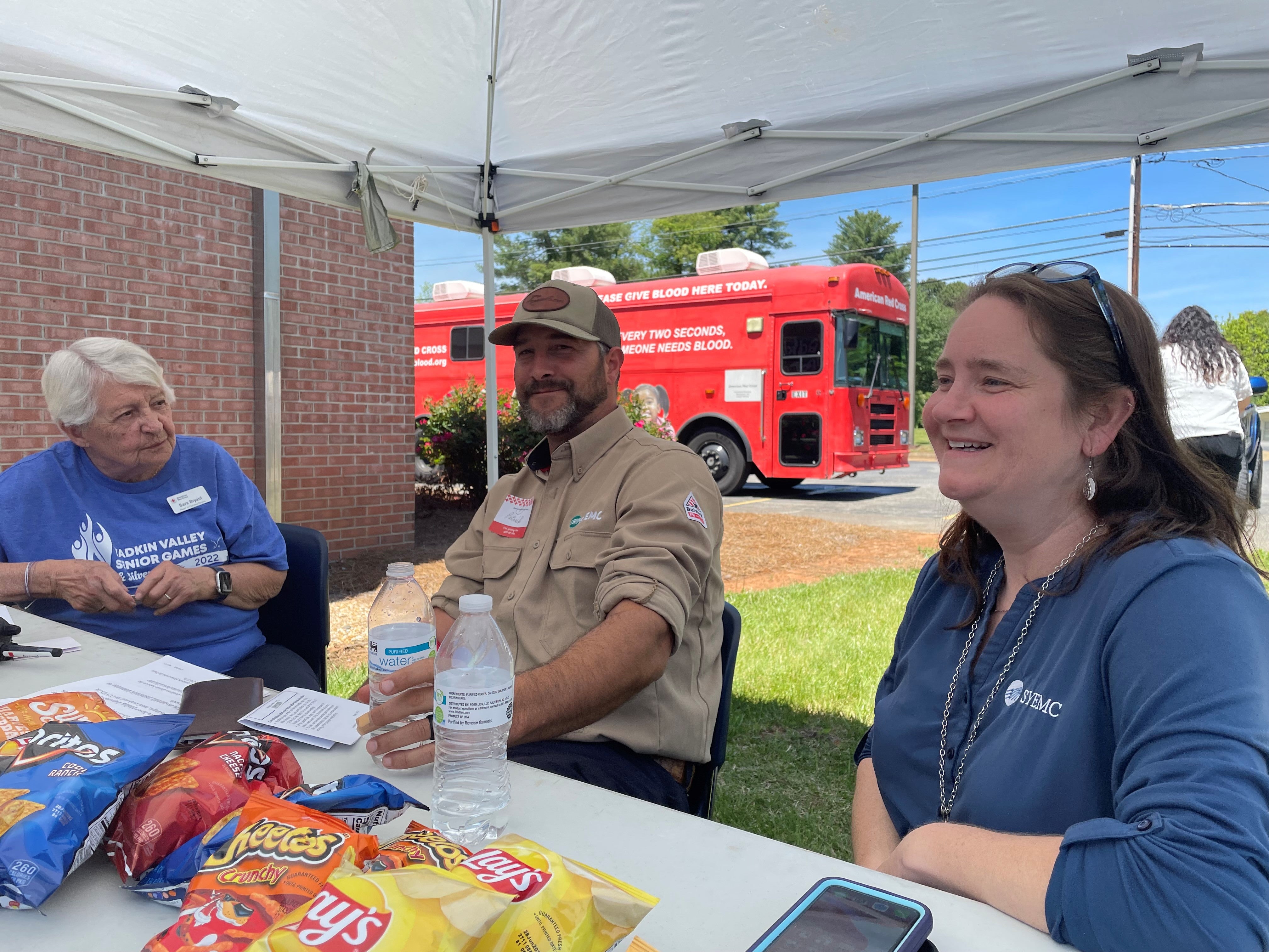 Sarah Bryant and Wendy Wood assist Patrick Frazier while he prepares to donate.